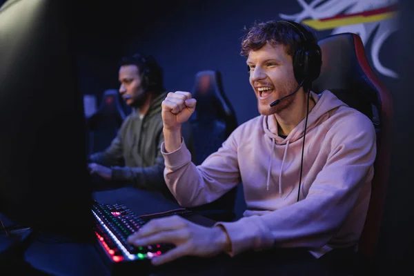 An excited young GUMBALL gamer with a headset at a teen desk